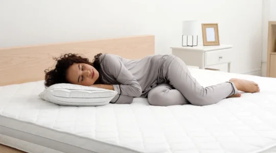 Une femme allongée sur le côté sur un matelas glisse sa main entre ses lombaires et le matelas pour tester le maintien.